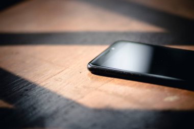 Ahşap bir masada büyük ekranlı siyah bir cep telefonu.