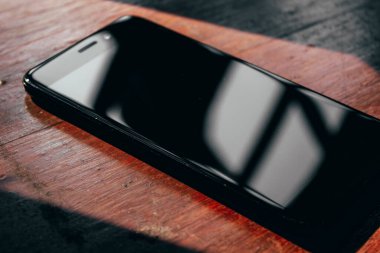 Ahşap bir masada büyük ekranlı siyah bir cep telefonu.