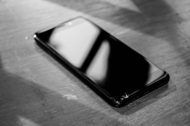 Ahşap bir masada büyük ekranlı siyah bir cep telefonu.