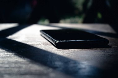 Ahşap bir masada büyük ekranlı siyah bir cep telefonu.