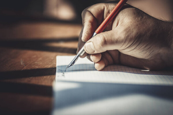 Красная ручка в руке человека, пишущего