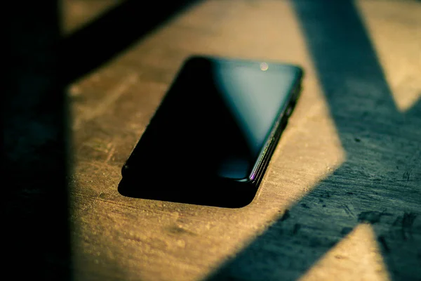木製のテーブルの上に大きなディスプレイと黒の携帯電話 — ストック写真