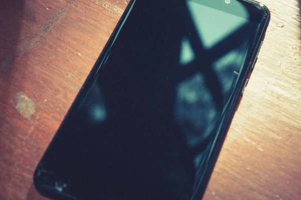 Black mobile phone with a large display on a wooden table