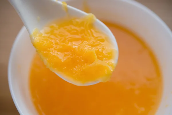 Lingură scoaterea sucului proaspăt de portocale cu un castron plin pe fundal — Fotografie, imagine de stoc