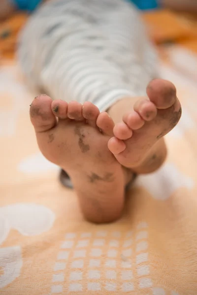 Junge liegt mit schmutzigen Füßen im Bett — Stockfoto