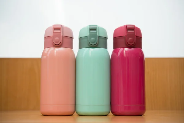 Colorful thermos on a wooden table — Stock Photo, Image