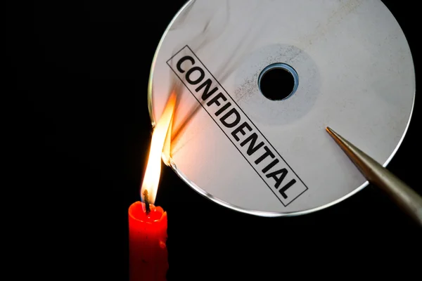 Burning a confidential compact disc with candle in dark — Stock Photo, Image