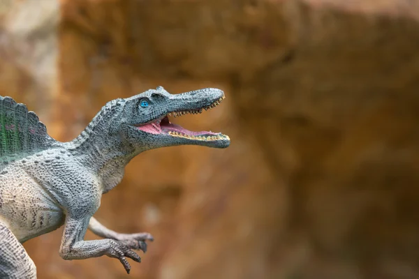 Grijze spinosaurus speelgoed tegenover rock berg — Stockfoto
