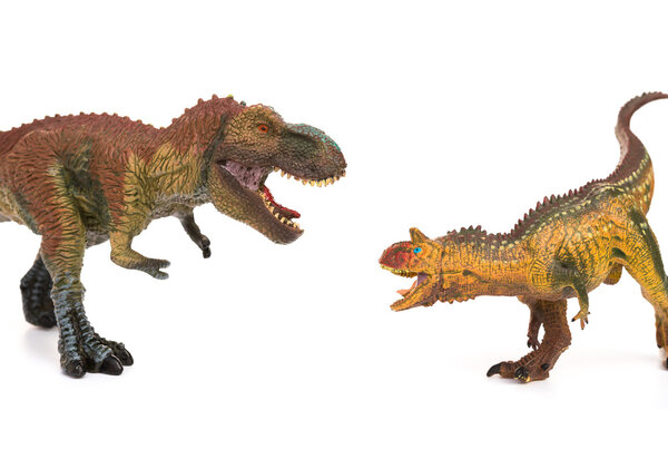 tyrannosaurus and carnotaurus toys on white