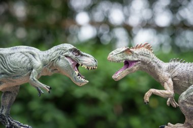 Tyrannosaurus ve allosaurus oyuncak önünde ağaçlar