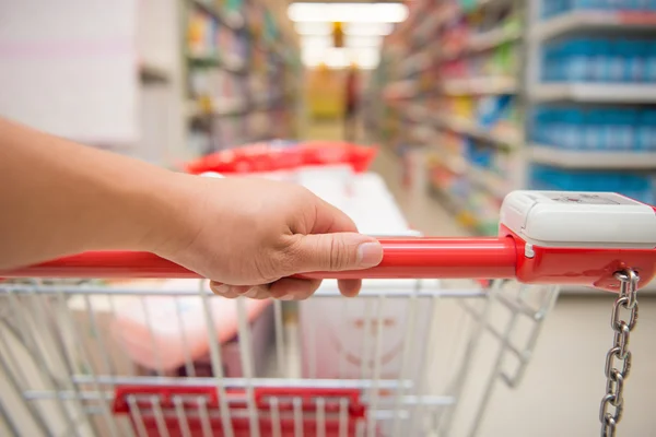 Hand duwen van een volledig gevuld winkelwagentje — Stockfoto