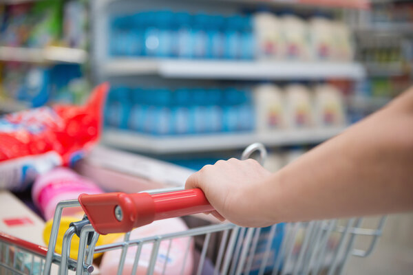Lady shopping with a full filled cart in a supermarket
