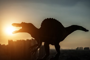 Silhouette spinosaurus ve günbatımı zamanı binalarda