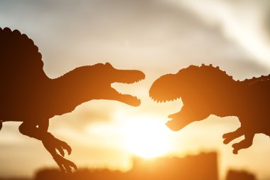 Silhouette spinosaurus ve tyrannosaurus ile günbatımı zamanı kadar sonunda binalarda