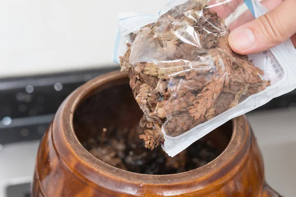 Putting bag of herbal to an enamel pot to decoct herbal medicine — Stock Photo, Image