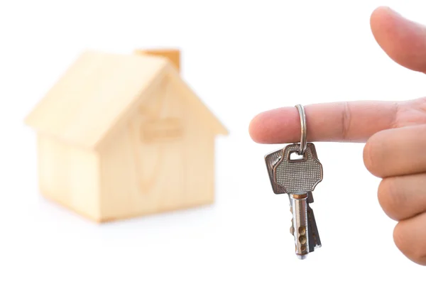 Holding keys in front of a house model on white — Stock Photo, Image