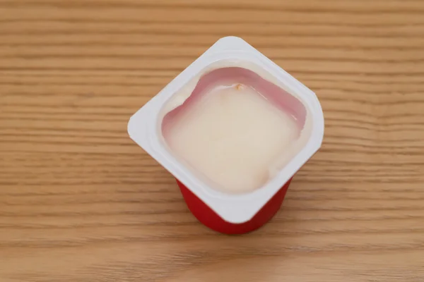 Bovenaanzicht kopje verse yoghurt zojuist geopend op een houten tafel — Stockfoto