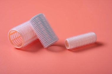 Pembe arka planda üç farklı boyutta saç bigudisi.