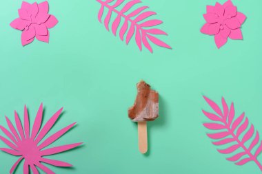 Üst manzara çoğunlukla buzlu çikolatayı yedi. Kağıt kesme, çiçek kesme ve yeşil arka planda yapraklar.