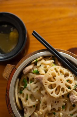 Nilüfer kökünden dilimlenmiş kızarmış domuz eti ve bir kase dikey çorba.