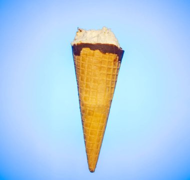 Çikolata ve vanilya aromalı dondurma külahında mavi arka planda ısırıklar var.