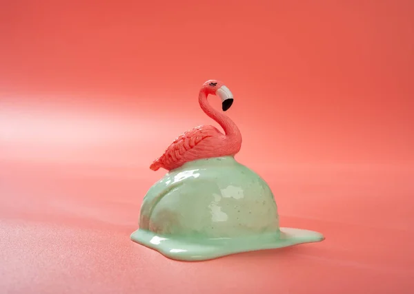 side view hami melon flavor ice cream ball starts melting with a flamingo on top on a pink background