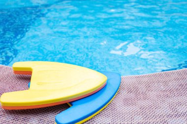 Yüzme havuzunun yanında yüzen sarı ve mavi pedler.