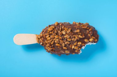 Üstünde kavun çekirdekleri ve mavi arka planda bir ısırık olan çikolatalı buzlu dondurma.