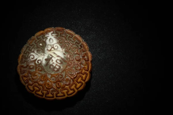 English translation of the Chinese-fortune-top view badly moldy moon cake on a dark background