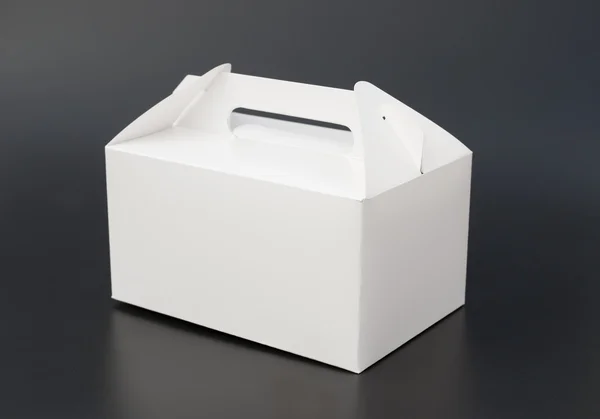 手里拎的黑色背景上的白色盒子 — 图库照片