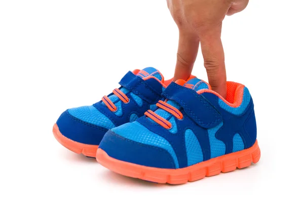Fingrar att sätta i ett par blå sportiga skor för barn på vit — Stockfoto