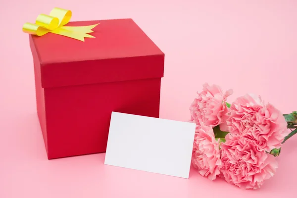 Cutie de cadou roșu și garoafe roz cu un card gol gata pentru text — Fotografie, imagine de stoc