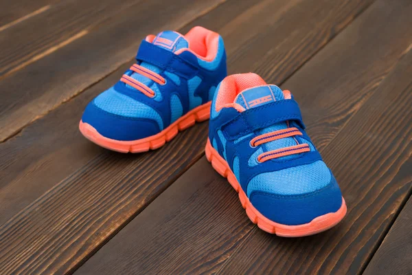 Pair of blue sporty shoes for kid on wood — Stock Photo, Image