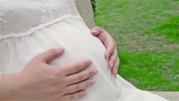 Jeune femme enceinte battant du ventre sentant le bébé, vue latérale et gros plan — Video