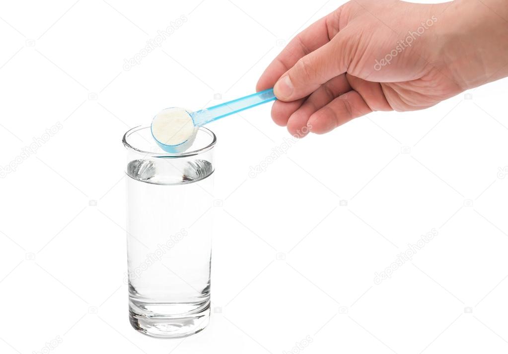 Putting powdered milk into a glass cup with clipping path — Stock Photo