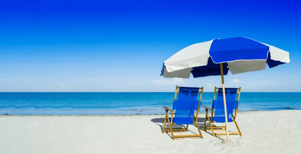 Tumbonas y sombrilla sobre arena plateada, concepto de vacaciones — Foto de Stock