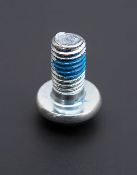 Round head bolt with blue loctite on a black background — Stock Photo, Image