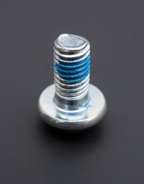 Round head bolt with blue glue on a black background — Stock Photo, Image