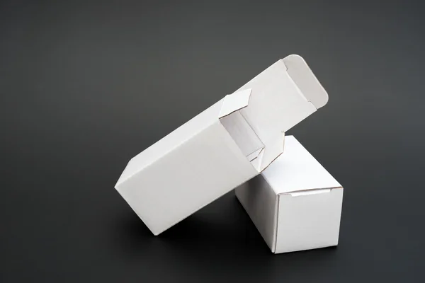 Zwei weiße Schachteln mit einem geöffneten und einem geschlossenen auf schwarz — Stockfoto