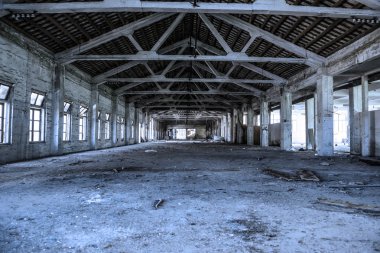 Empty industrial loft in an architectural background with bare cement walls and floors, blue tone