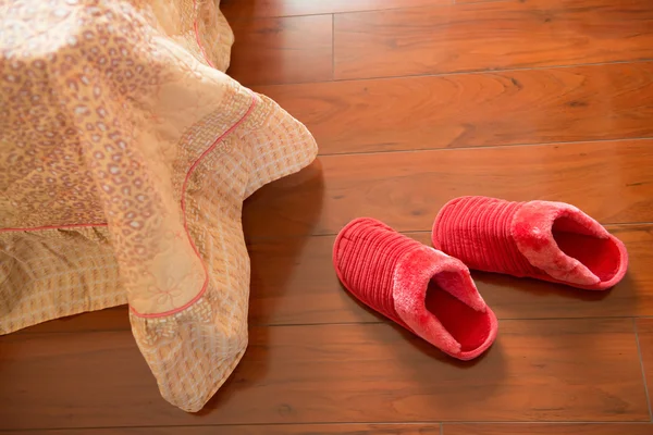 Par de zapatillas blancas en el suelo cerca de una cama —  Fotos de Stock