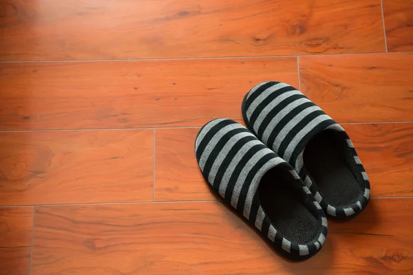 Pair of black slippers on a wooden floor — Stock Photo, Image