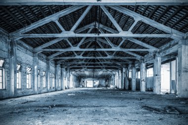 Empty industrial loft in an architectural background with bare cement walls, floors and pillars supporting a mezzanine blue tone
