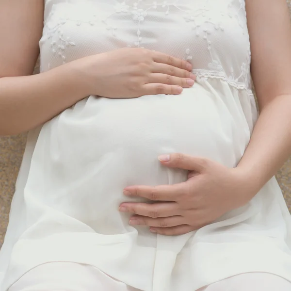 Молодая беременная женщина кладет руки на живот, чувствуя своего ребенка, квадратная композиция — стоковое фото