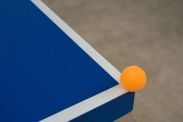 Bola de pingpong golpea la esquina de una mesa de pingpong azul — Foto de Stock