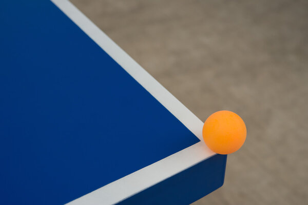 Pingpong ball hits the corner of a blue pingpong table