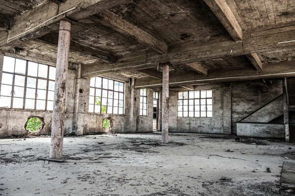 Empty industrial loft in an architectural background with bare cement walls, floors and pillars supporting a mezzanine