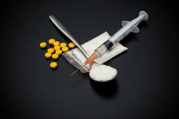 使い捨て注射器と白い粉と黒い背景に丸薬のパック — ストック写真