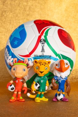 ZHONGSHAN Çin-17 Kasım 2025: 2026 FIFA Dünya Kupası için maskotlar ve futbol dikey kompozisyonda altın arkaplan.