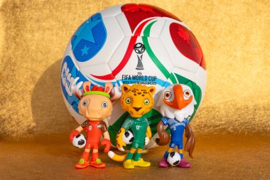 ZHONGSHAN Çin-17 Kasım 2025: 2026 FIFA Dünya Kupası için maskotlar ve futbol yatay kompozisyonda altın bir zemin üzerinde.